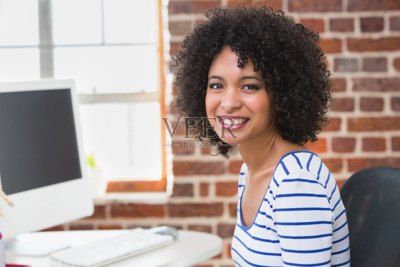 微笑女性照片编辑器使用电脑在办公室图片素材