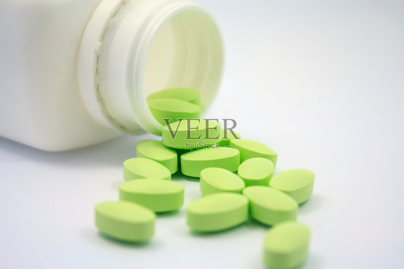 绿色药片和白色背景上的药瓶